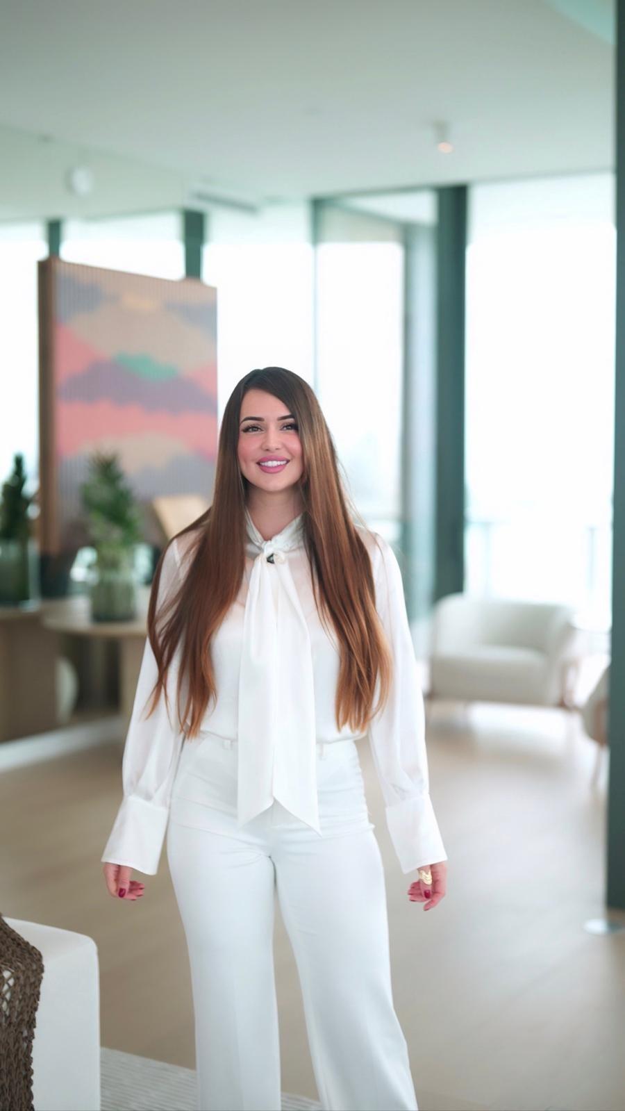 Stefania Riverin in a Miami condominium residence, floor-to-ceiling glass behind her