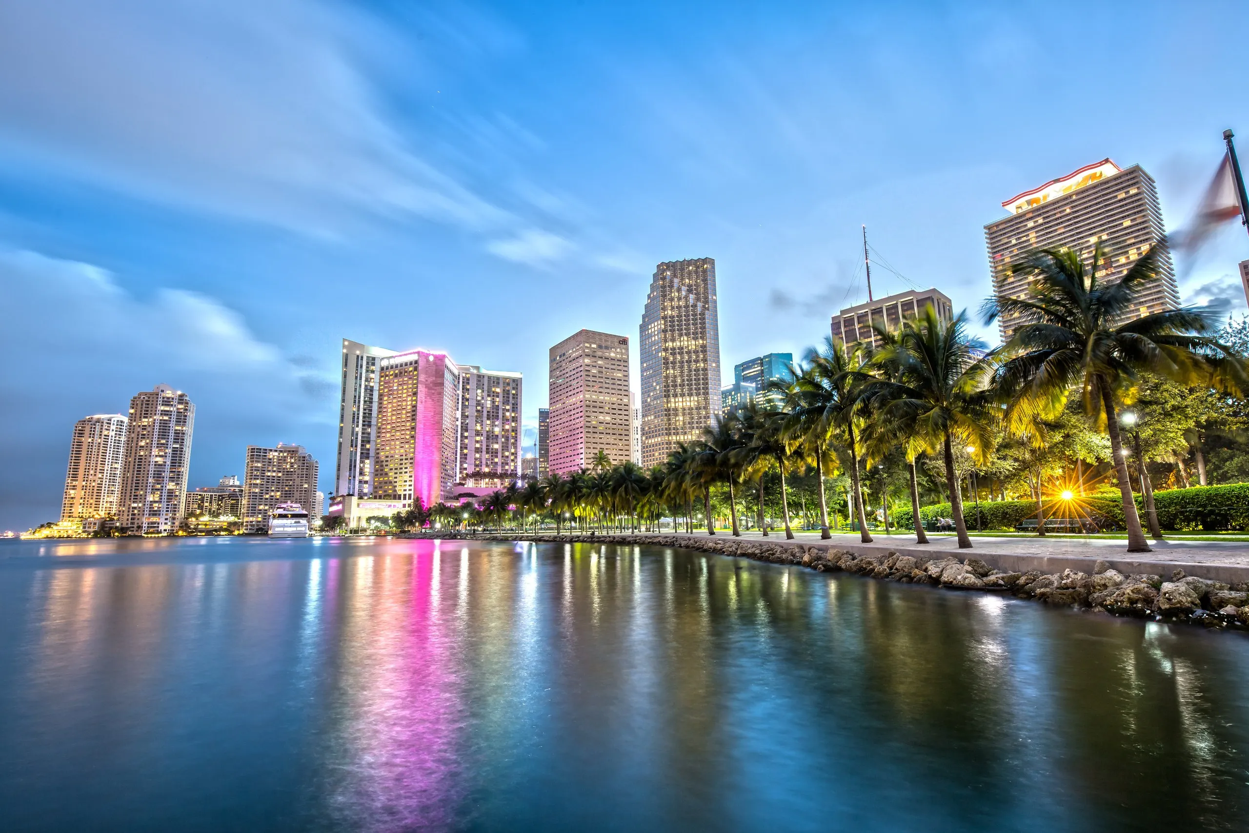 Downtown Miami at dusk seen from the Bayside waterfront, palms along the bay and towers reflected in the water
