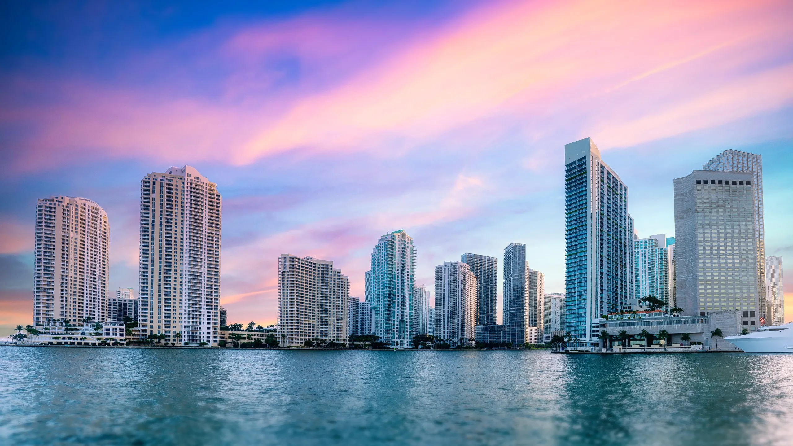 The Miami skyline seen from Biscayne Bay under a pink and violet sunset sky